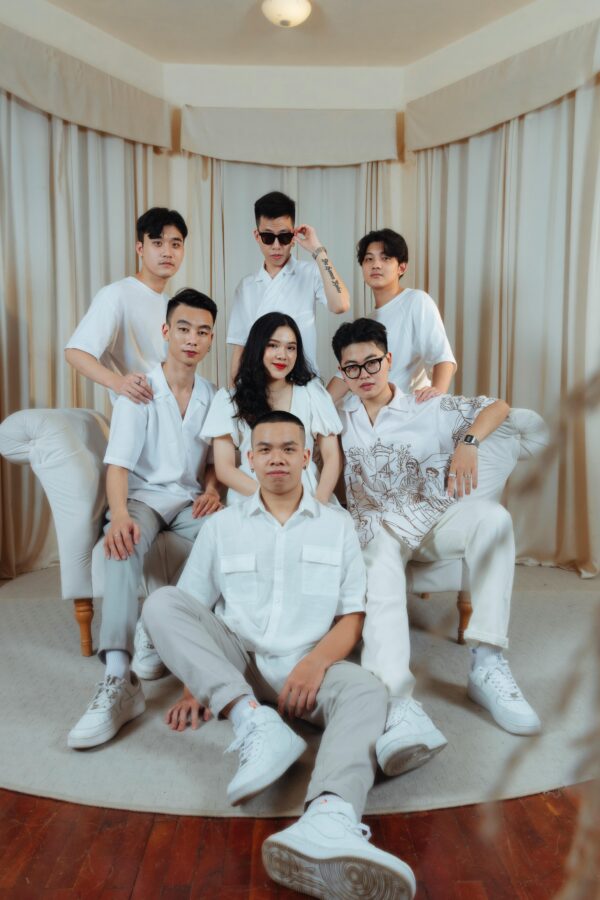 Stylish group of seven friends posing in a studio setting dressed in white.