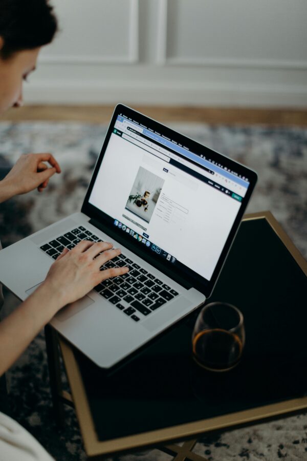 Close-up of a person working remotely on a laptop indoors. Ideal for remote work or technology themes.