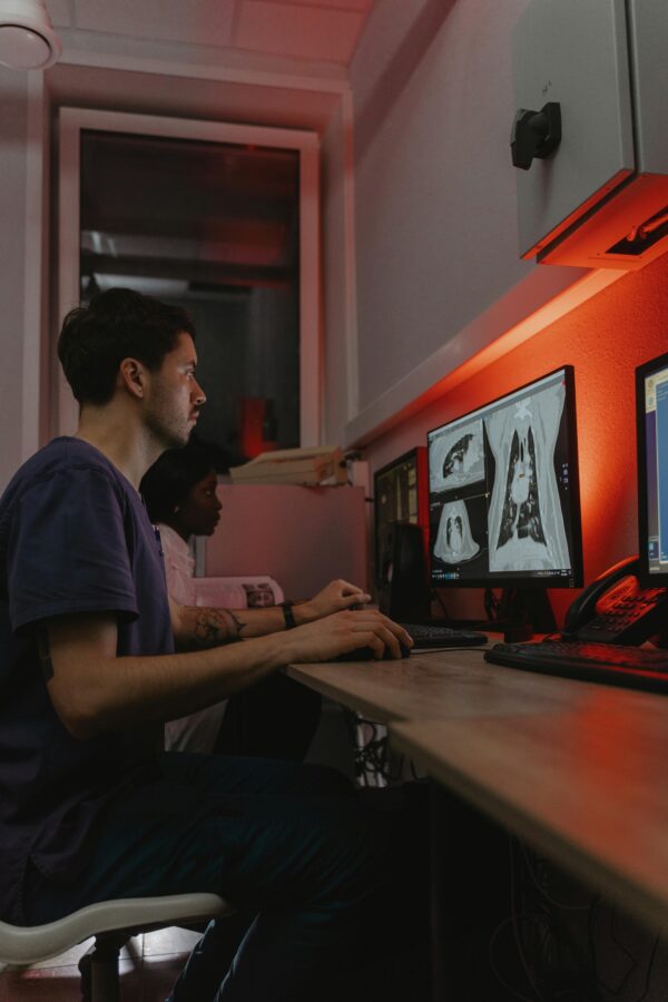 Doctors reviewing diagnostic X-ray images on computer in a clinical setting.