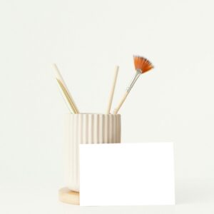 Elegant minimalist desk scene with ceramic holder and brushes for artistic pursuits.