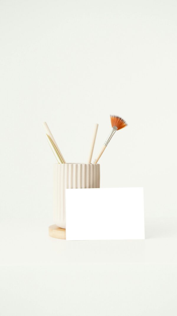 Elegant minimalist desk scene with ceramic holder and brushes for artistic pursuits.
