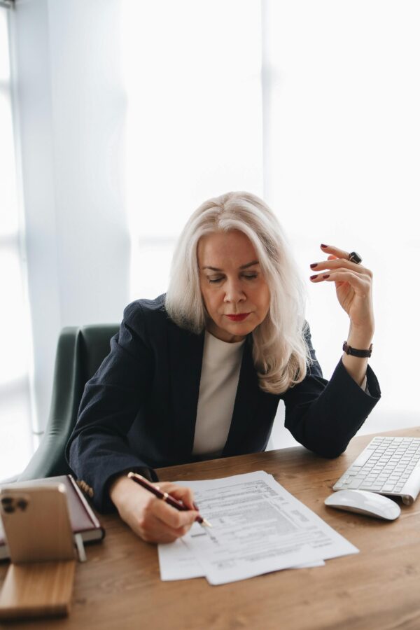 Senior woman in office reviewing documents, showcasing professional work environment.