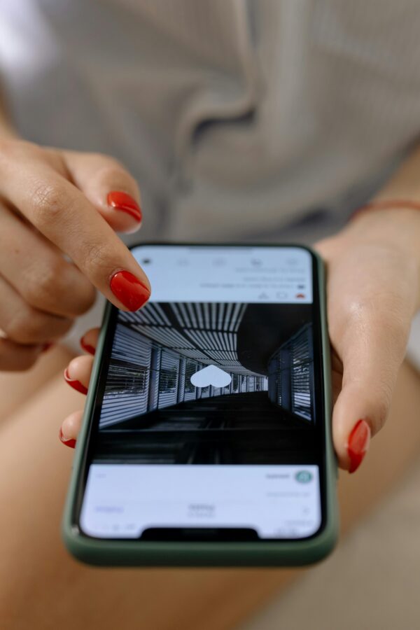 A woman with red nails uses a smartphone to browse social media indoors.