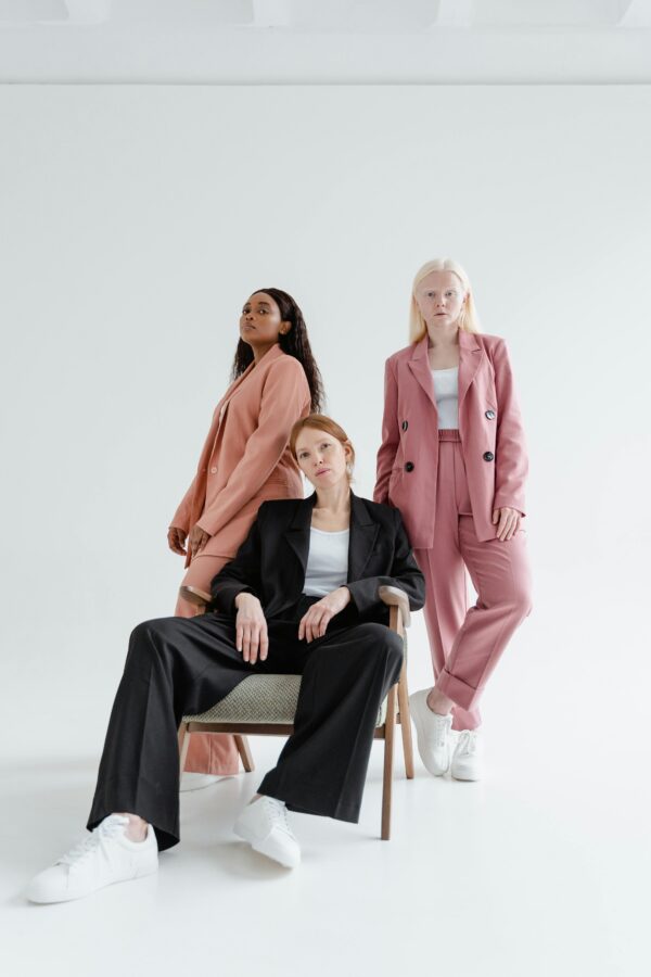 Three diverse women in stylish business suits pose confidently against a white background.