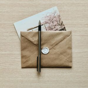 A classic brown envelope with a wax seal and pen atop a wooden desk, evoking a vintage feel.