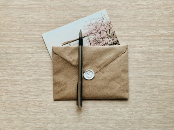 A classic brown envelope with a wax seal and pen atop a wooden desk, evoking a vintage feel.